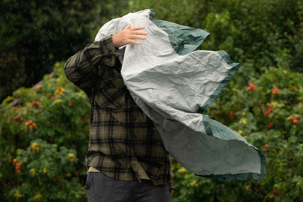 A tourist struggles with his poncho in strong wind  in Bar Harbor, Maine. 