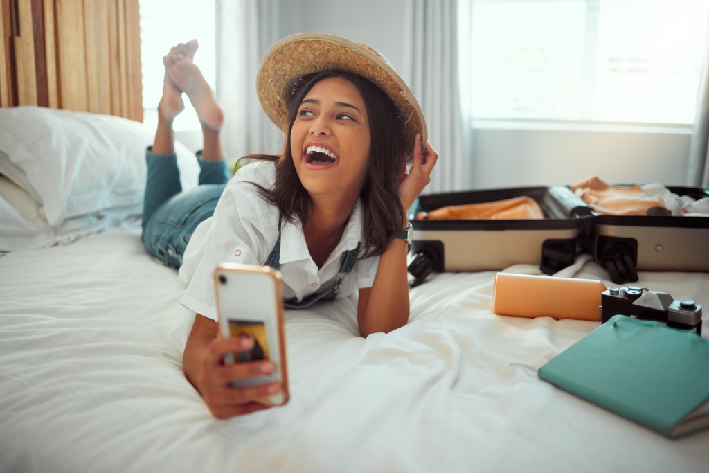 Travel, suitcase and phone with woman in bedroom of hotel. 