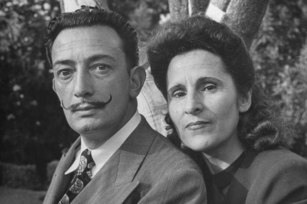 Salvador Dali and his wife Gala pose in a black and white picture.