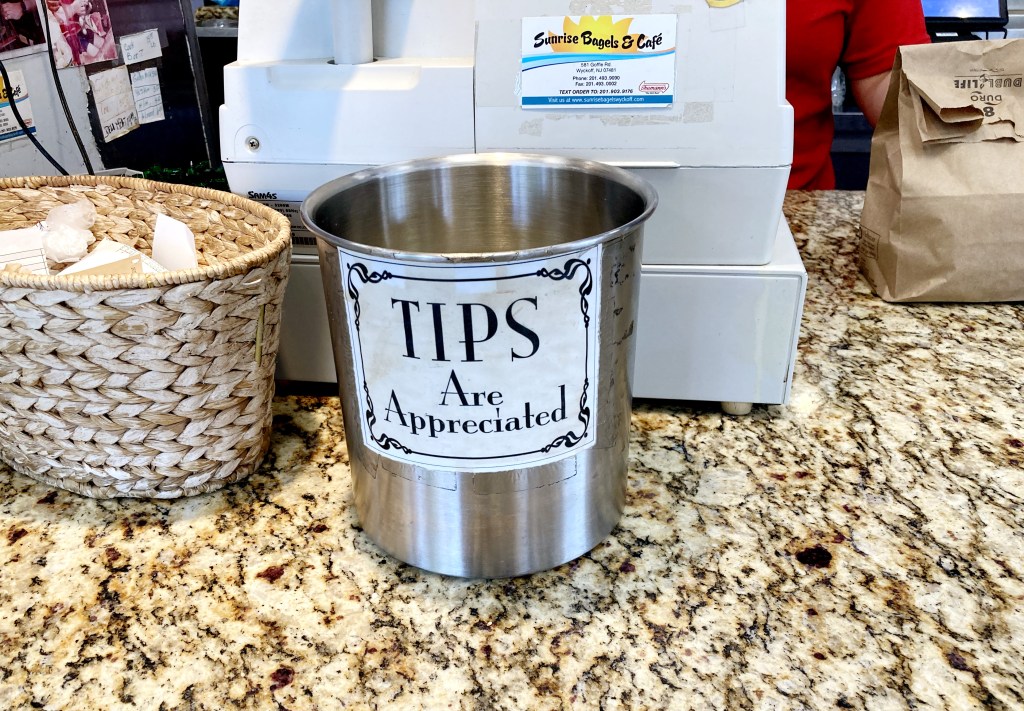 A tip jar that reads "tips are appreciated" in a bagel shop, Wyckoff, NJ. Photo by Christopher Sadowski. 