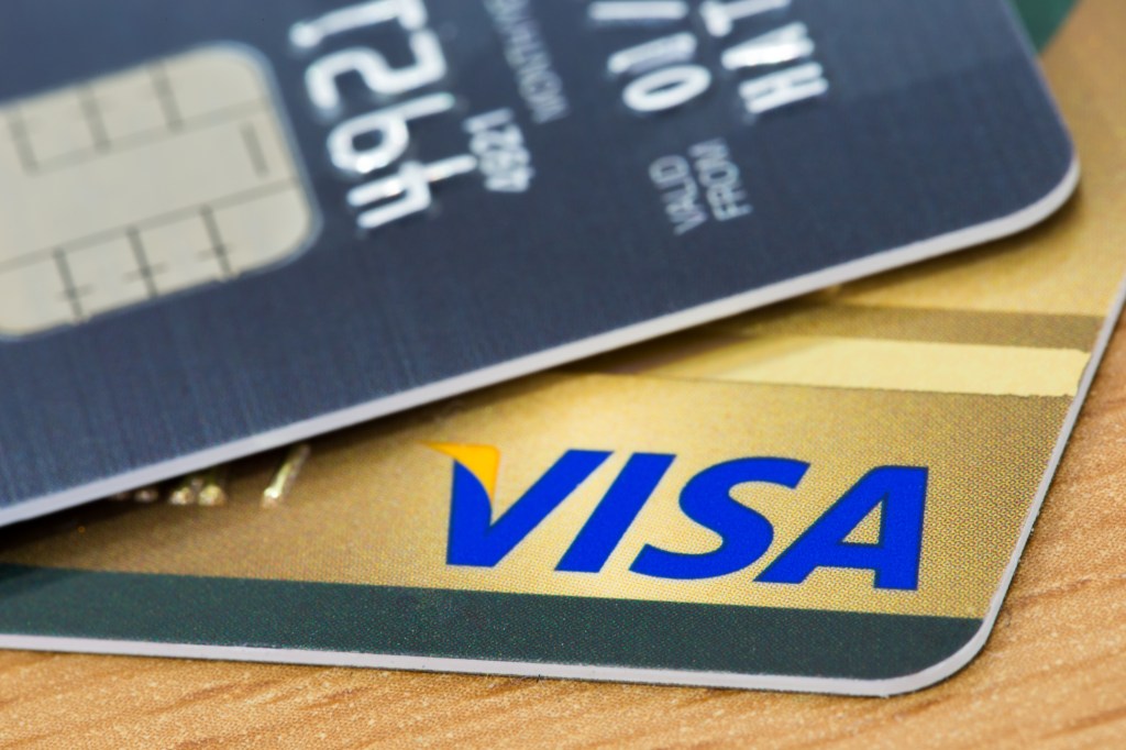 Closeup of a VISA credit card with smart chip on wood background texture.