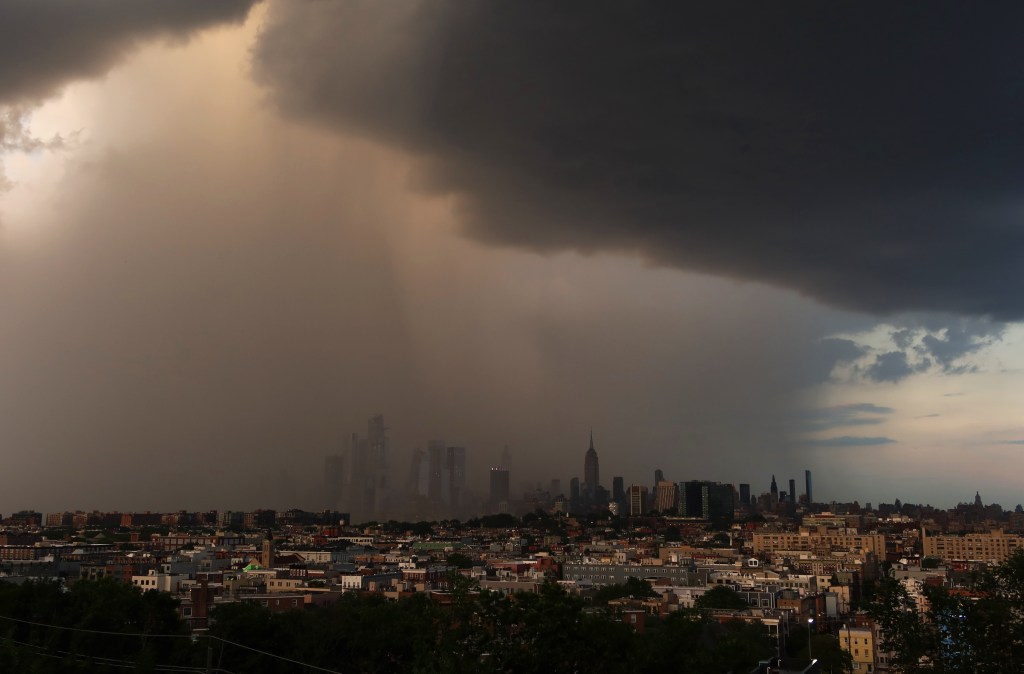 A short, intense rain shower passes over the midtown Manhattan skyline, Hudson Yards and the Empire State Building as the sun sets in New York Cit
